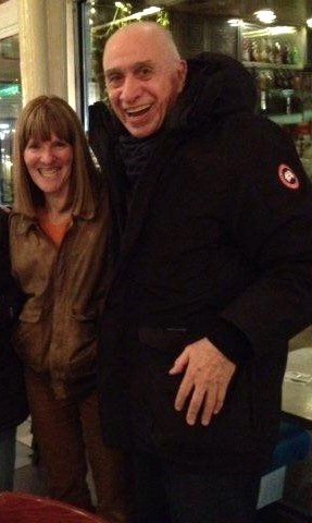 Dick, a stately, balding older man in a dark blue winter jacket poses with Elly in a brown leather coat and brown corduroy slacks in a Sushi restaurant on the upper west side of NYC.