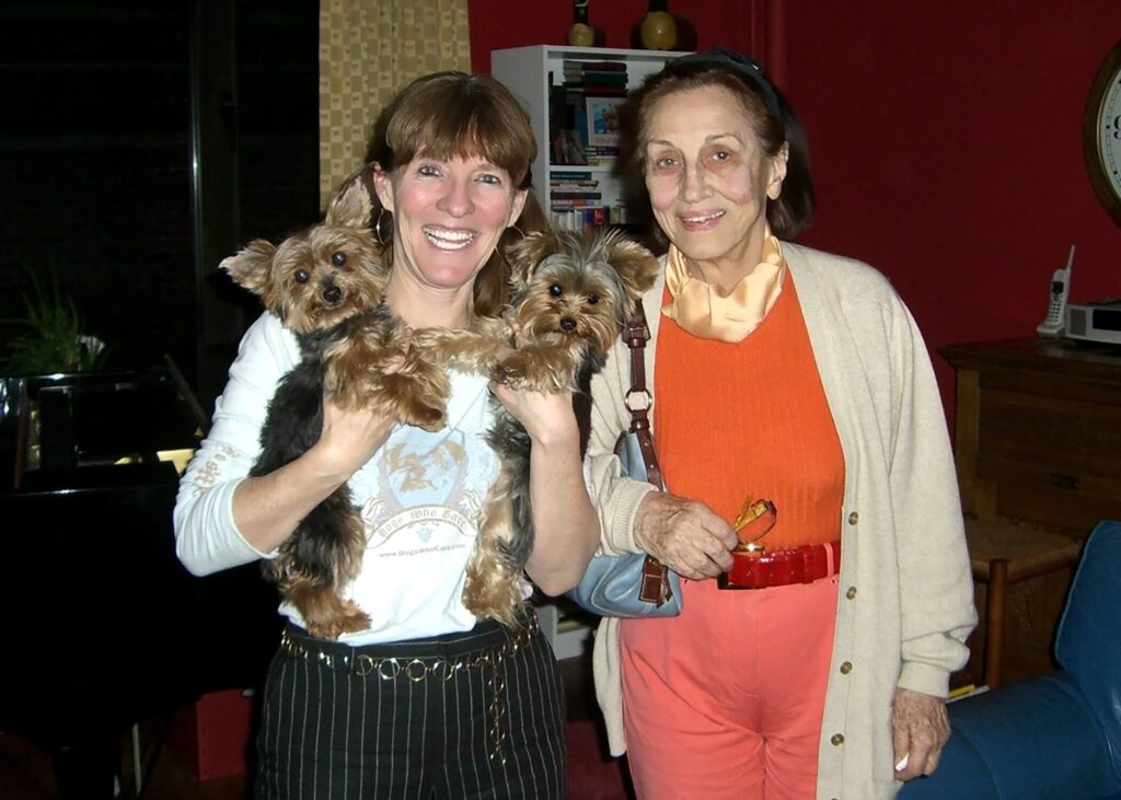 Elly McGuire, standing up and holding her two Yorkshire Terriers, poses with Francoise Gilot, a famous artist and mistress of Picasso.