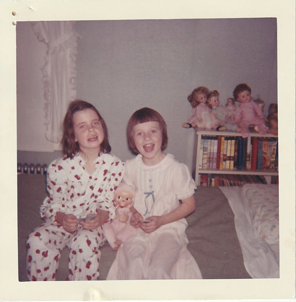 Two little girls sitting on a bed for a slumber party. Circa 1960.