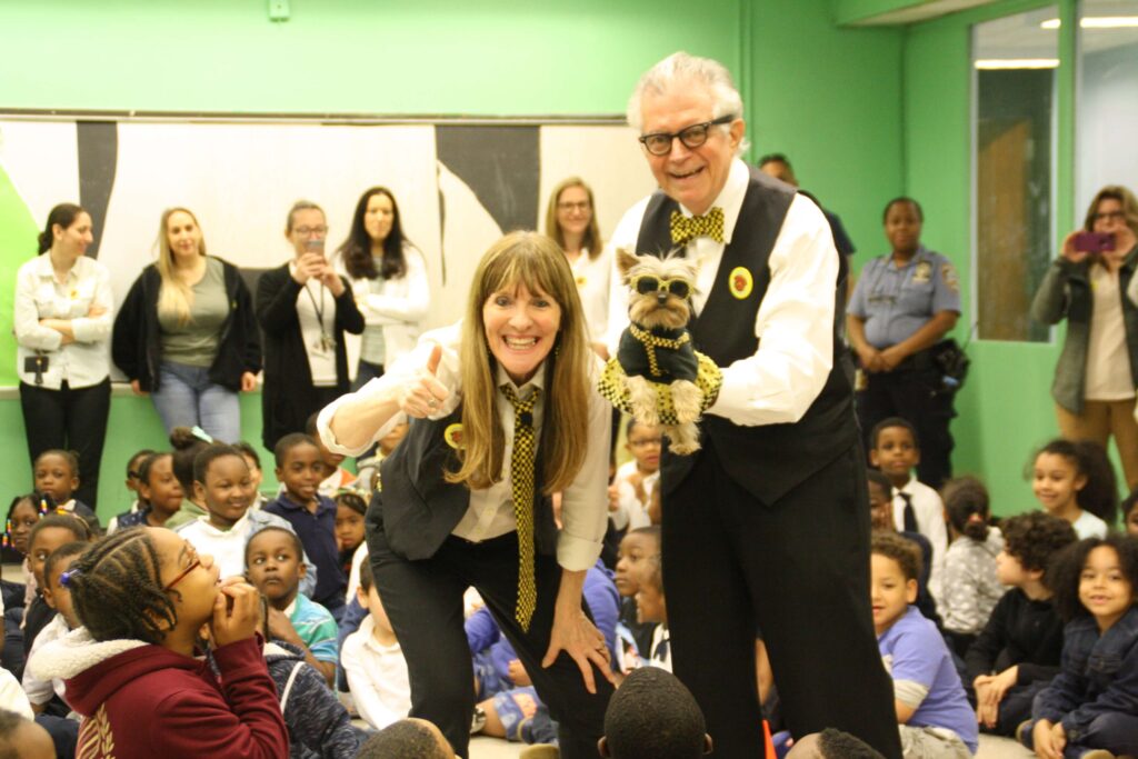 Tiny Yorkshire terrier, Schmitty The Weather Dog, poses in taxi style outfit by New Yorkie with her co-stars, author Elly McGuire and Meteorologist Ron at a Schmitty The Weather Dog Science Sing-Along Show at a school in New York.